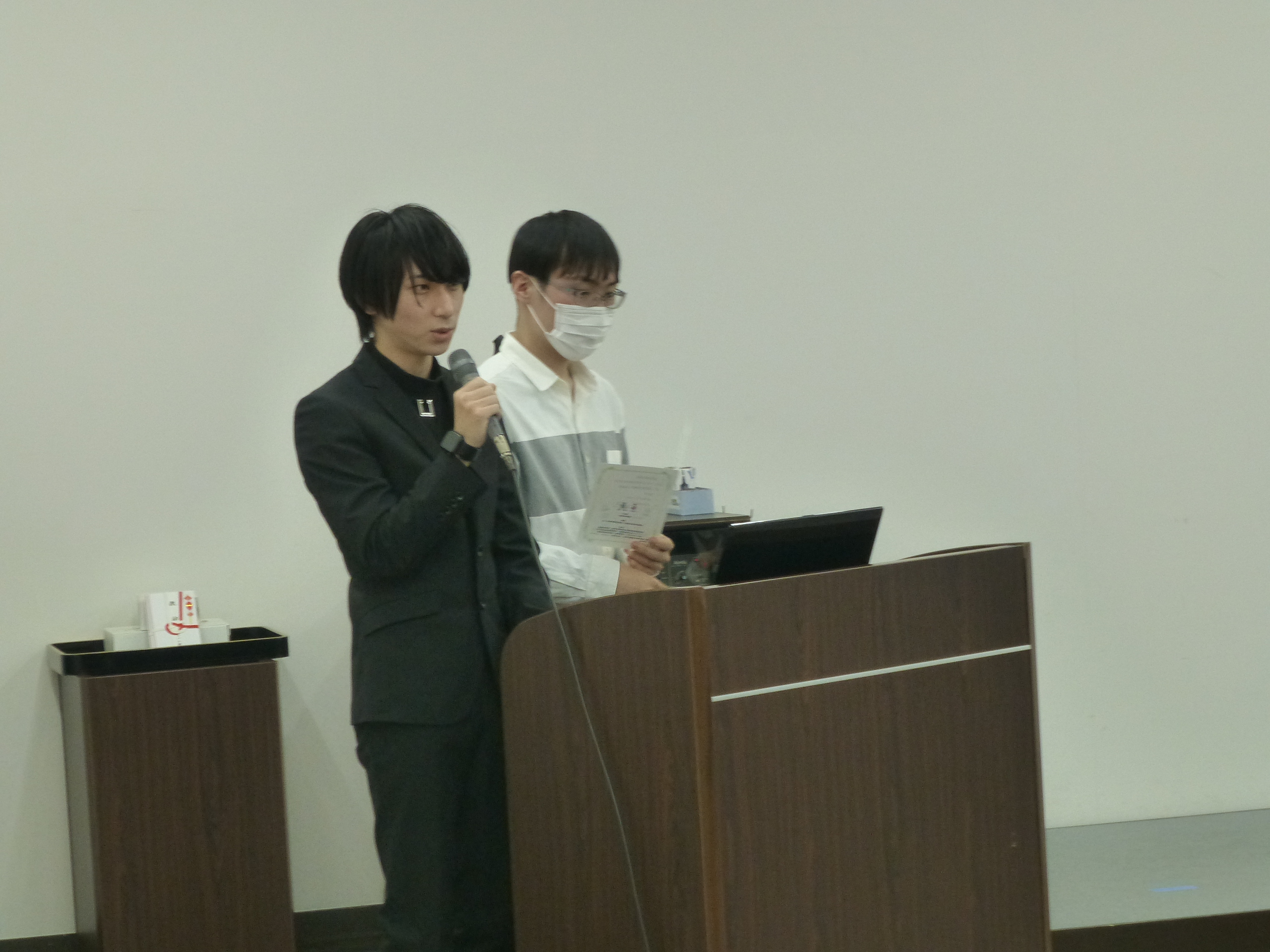 Two representatives from the broadcasting club explaining their works